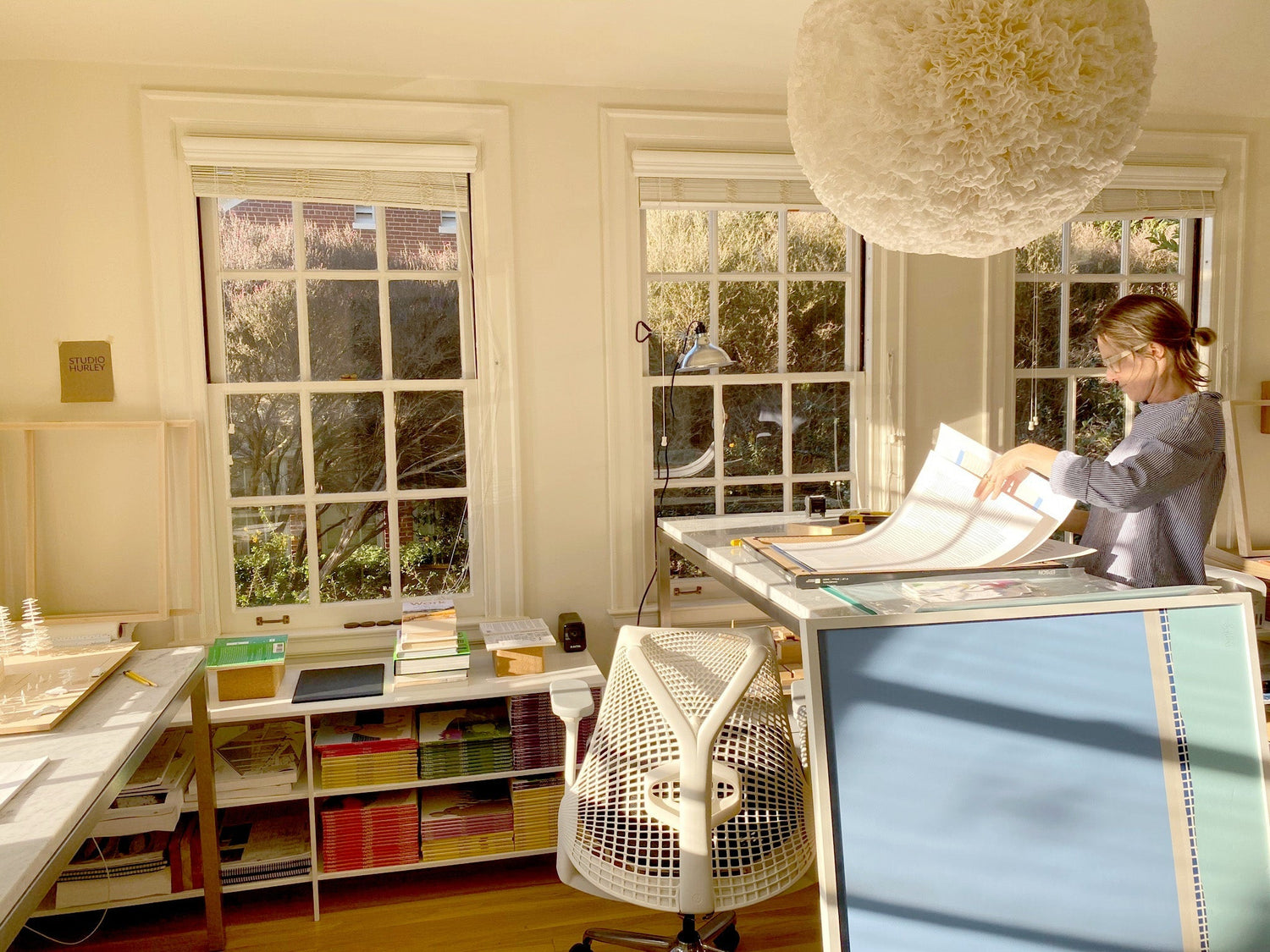 Jorey working at a desk in a sunlit room with large windows